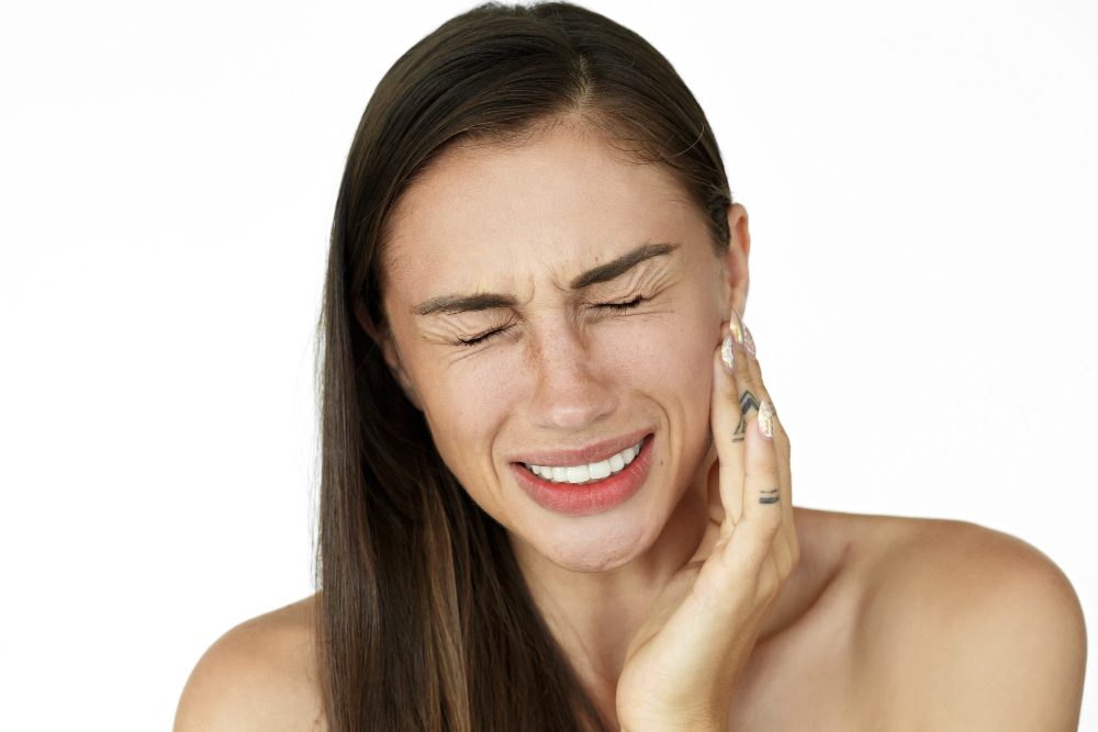 woman holds fingers her cheek showing toothache